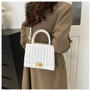 Detail of white PU leather crossbody bag with vertical quilting and gold hardware lock
