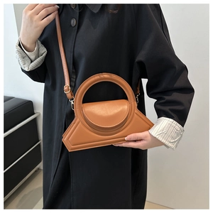 Detailopname van de bruine leren handtas met trapeze-ontwerp en rond handvat