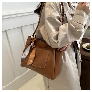 Détail d'un sac cabas caramel avec foulard en soie, texture grainée et bandoulière tressée