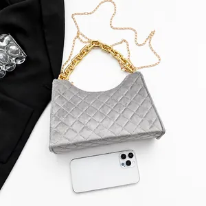 Detailansicht der grauen Stepptasche mit Goldkette im Vergleich zum Smartphone