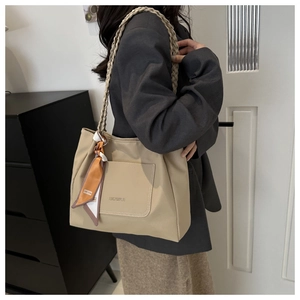 Détail du sac cabas beige avec poignée en corde tressée et foulard en soie orange