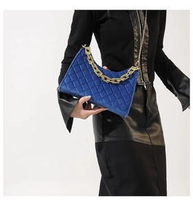 Detail der blauen gesteppten Samttasche mit goldener Kette auf einem Model-Outfit