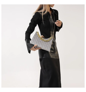 Details der grauen Stepptasche mit goldener Kette und weicher Wildleder-Textur