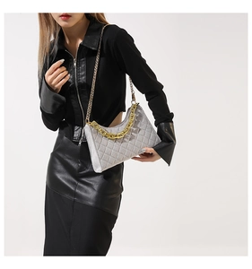 Detail der grauen Stepptasche mit klobigem Goldgriff und metallischem Schultergurt