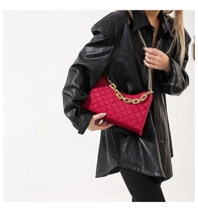 Nahaufnahme der roten gesteppten Samthandtasche mit goldener Kette an einem Model
