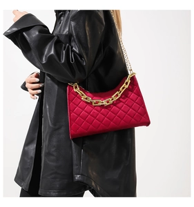 Detail der roten gesteppten Samthandtasche mit goldener Kette getragen zur schwarzen Lederjacke