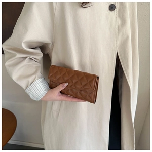 Close-up of brown quilted long wallet with elegant diamond stitching held by model