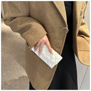 Close-up of white quilted long wallet tucked into a brown tweed blazer pocket