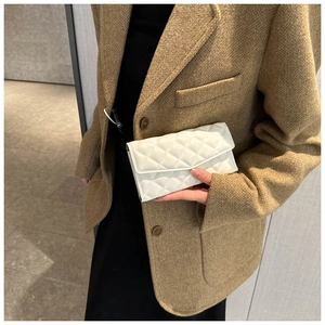 Détail macro du motif de broderie matelassé blanc sur une pochette élégante en cuir