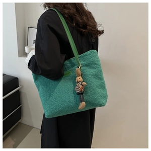Dettaglio della borsa tote verde in pelliccia con etichetta fashion e ciondolo a coniglio