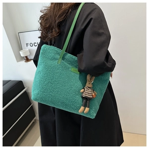 Dettaglio della borsa tote in pile verde con etichetta in pelle e ciondolo a coniglio
