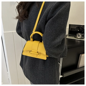 Close-up of bright yellow hourglass handbag with lychee texture leather on wool coat