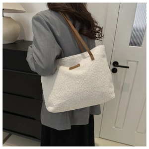 Dettaglio borsa tote in sherpa bianco con manici in pelle marrone ed etichetta