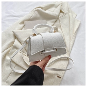 Detail der weißen Mini-Tasche aus Leder mit Litschi-Struktur und dekorativen Metallringen