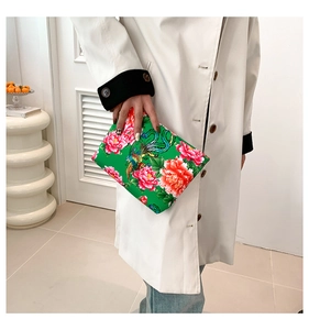 Dettaglio pochette con motivi di peonie rosse e fenici su tessuto floreale verde
