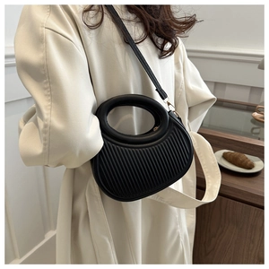Detailed view of black pleated dumpling bag with circular handle and gold hardware