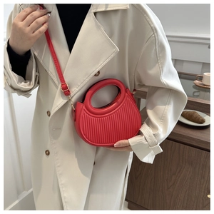 Detailed close-up of a red pleated crescent crossbody bag featuring an oval handle