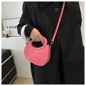 Detail of pink pleated crossbody bag with round hollow handle and gold-tone hardware
