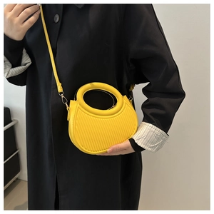 Close-up of bright yellow pleated crescent bag with circular handle and textured finish