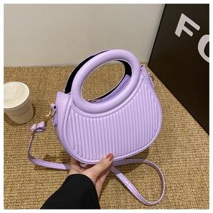 Detail of purple pleated handbag with round handle and vertical wave texture on straw mat