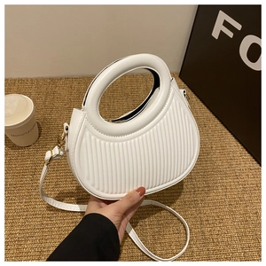Detail of white pleated PU leather handbag with unique circular cutout handle and strap