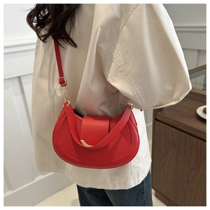 Detailed view of a red half-moon shoulder bag with gold metal buckle on a model