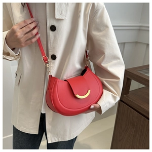 Borsa a tracolla rossa a mezzaluna con fibbia dorata indossata da una modella in interni moderni