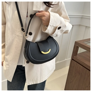 Detailed close-up of a black leather crescent saddle bag with a gold buckle and strap