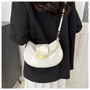 Minimalist white crescent shoulder bag with gold hardware on a black blazer