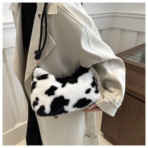 Detail of soft faux fur cow print underarm bag with braided shoulder strap on model