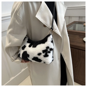 Fuzzy cow print shoulder bag shown on a model featuring a stylish crescent moon shape