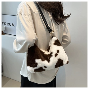 Detail of plush cow print shoulder bag with knotted leather strap and gold ring