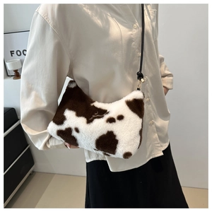 Detail of plush faux fur crossbody bag featuring stylish black and white cow print texture