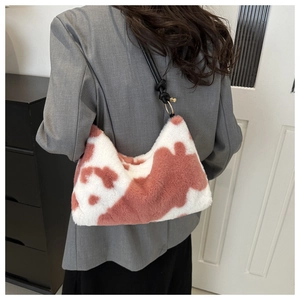 Detail of pink cow print plush shoulder bag with black leather strap and gold metal hardware
