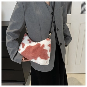 Close-up of pink cow print plush shoulder bag with black strap and gold metal rings