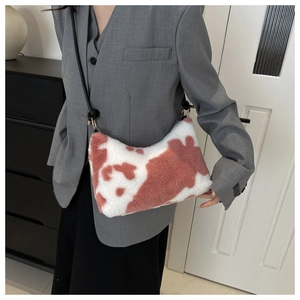 Detail of plush cow print underarm bag with golden rings and slim black shoulder strap