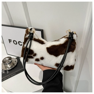 Close-up of plush cow print shoulder bag with black strap and soft furry texture