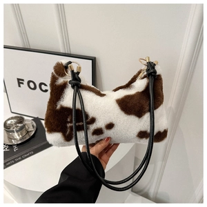 Detailed close-up of cow print faux fur hobo bag with gold hardware and black handle