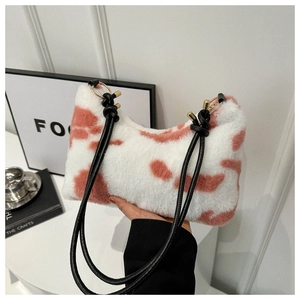 Detail of plush faux fur cow print shoulder bag featuring black knotted handles and gold rings