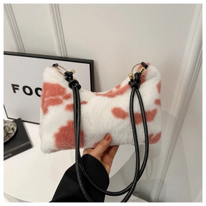Detail of pink cow print plush shoulder bag with long black straps and gold rings