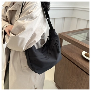 Detail of black crescent canvas tote bag with woven zipper pull and wide shoulder strap