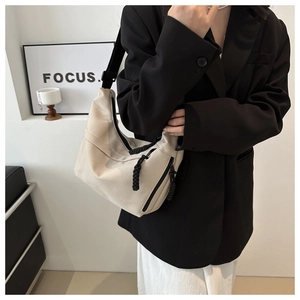 Detail of beige canvas crossbody bag featuring black woven zipper and wide shoulder strap
