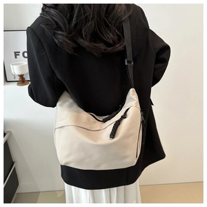 Model wearing a minimalist beige canvas crossbody bag with black cord zipper details