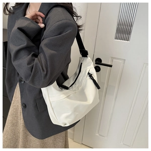 Close-up of minimalist off-white crossbody dumpling bag with adjustable black strap