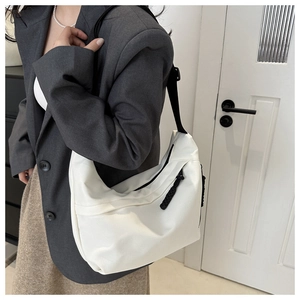 Close-up of white crescent crossbody bag with black adjustable strap on model