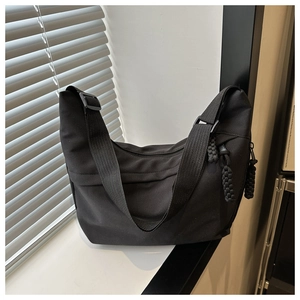 Detail of black nylon crossbody bag with adjustable wide strap and woven zipper puller