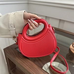 Red half-moon handbag with vertical stripes and round cutout handle in a hand-held view