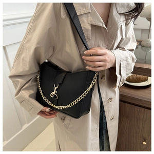 Detail view of black leather bucket bag featuring wide nylon strap and gold chain accent