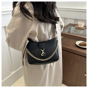 Detail of a black leather shoulder bag with gold metal chain and buckle on a side view