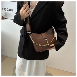 Detail of vintage brown leather bucket bag with wide fabric strap and gold chain link